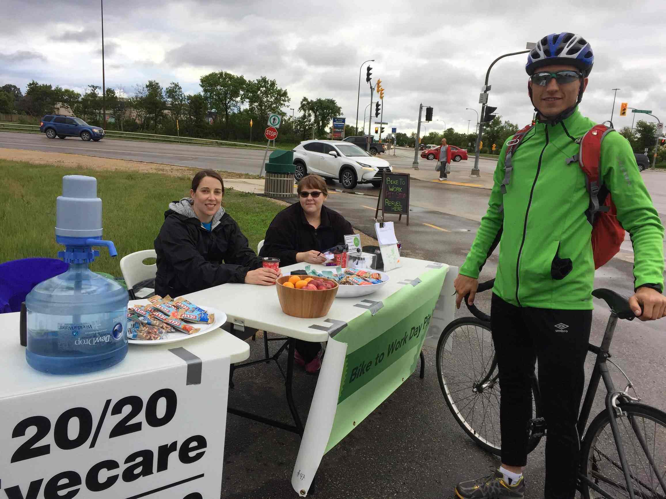 20/20 Staff posing with cyclist at pit stop table